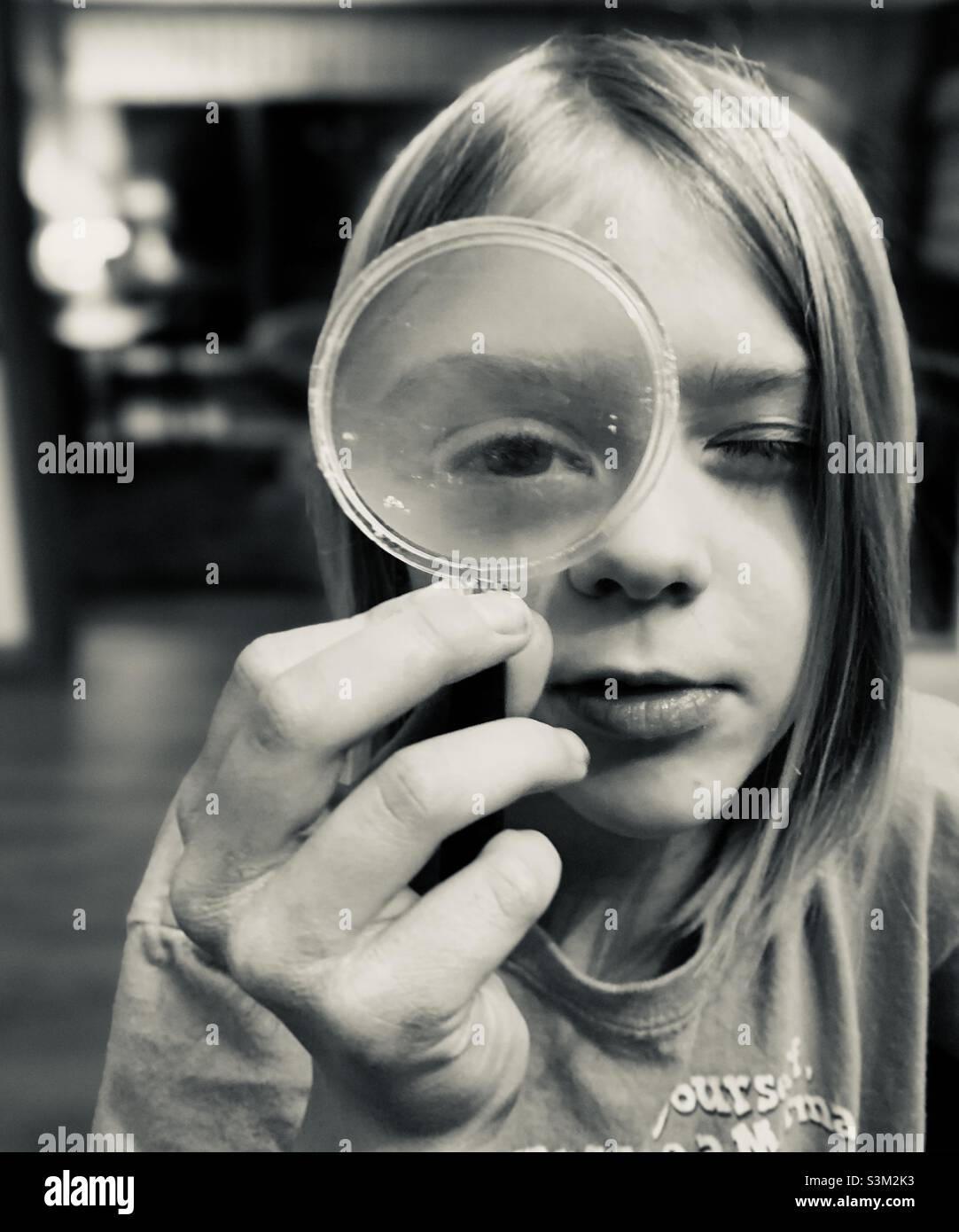 Bambino che tiene una lente di ingrandimento davanti al loro occhio. Foto Stock