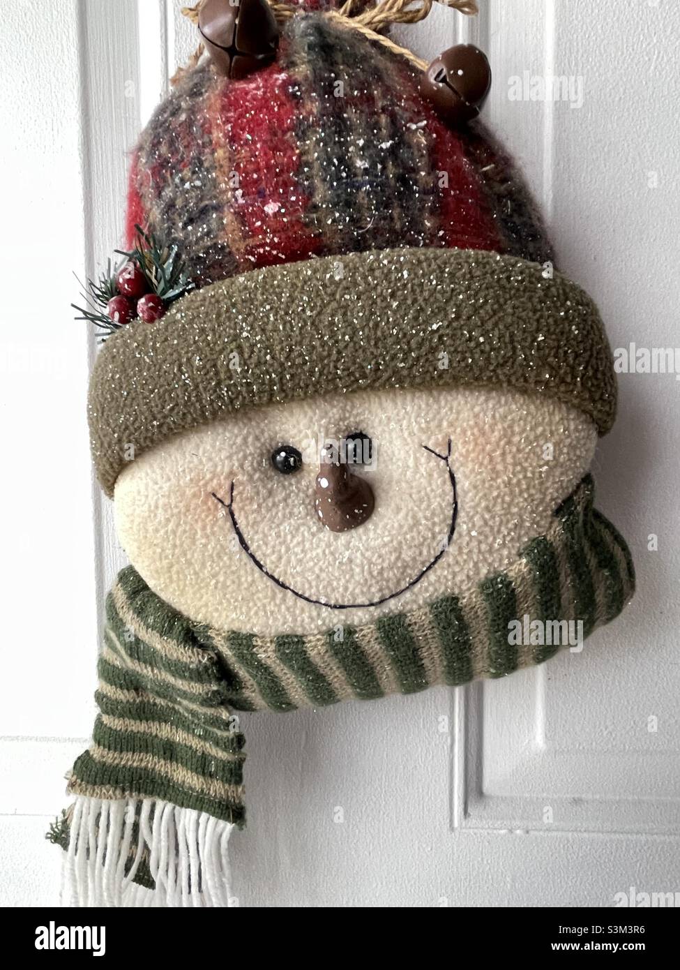 Un morbido pupazzo di neve in tessuto è appeso su una porta d'ingresso in Utah, USA, impacchettato contro il freddo, ovviamente felice con la stagione. - Immagine stock catturata con smartphone