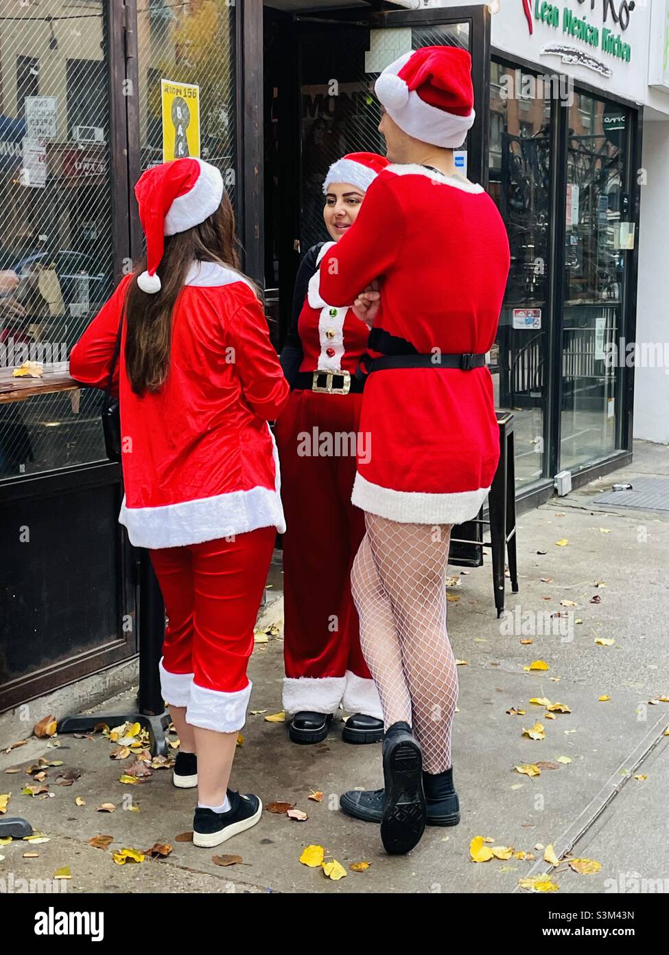 Tre persone vestite in abiti Babbo Natale godendo SantaCon New York City Dicembre 2021 Foto Stock