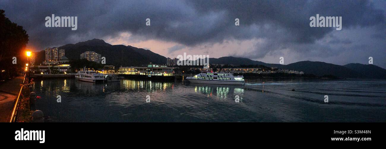 Un traghetto si avvicina al molo al crepuscolo, Discovery Bay, Lantau Island, Hong Kong Foto Stock