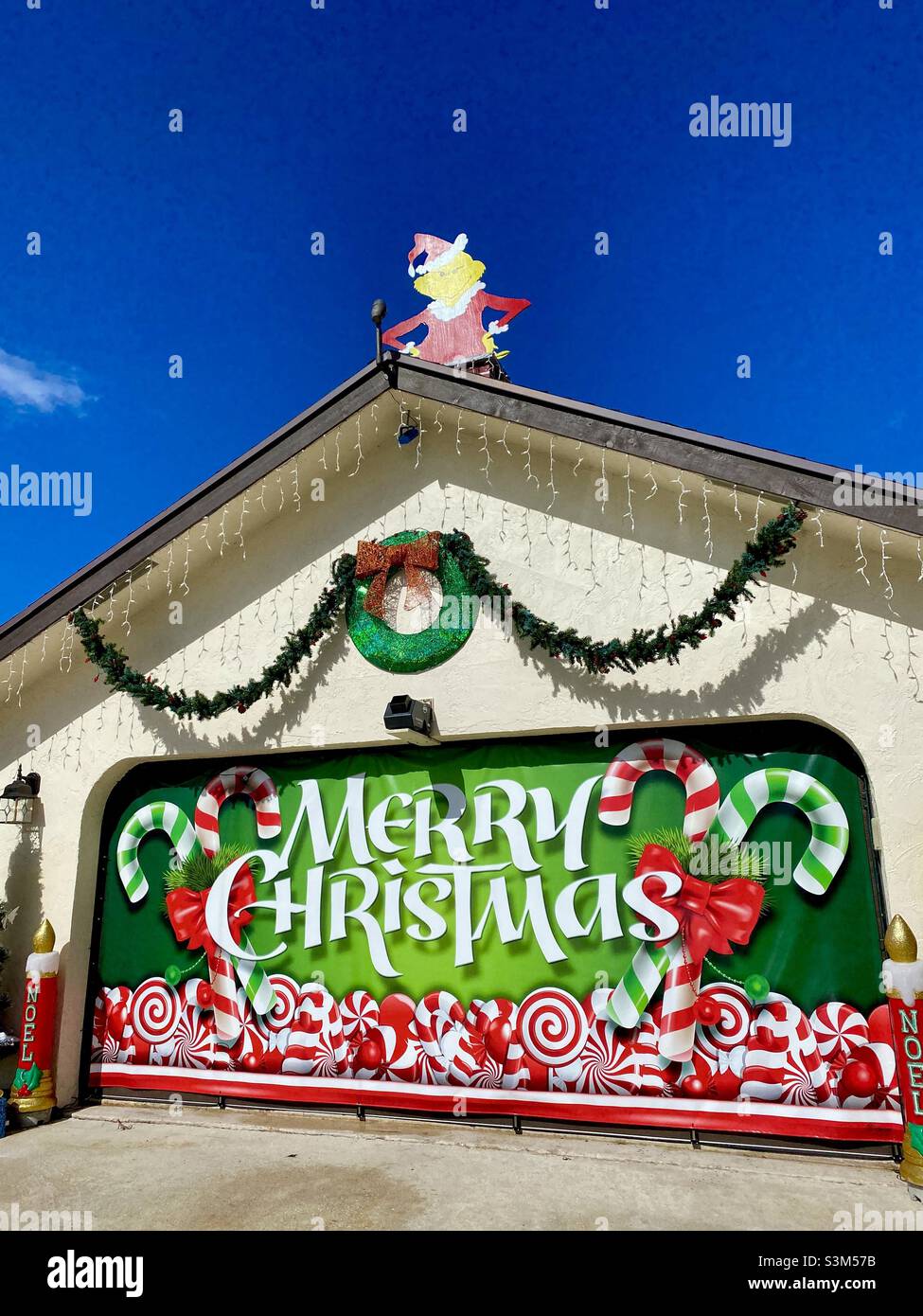 Tetto decorato e garage con un Grinch e un cartello di buon Natale sulla porta del garage di una casa di Floridian, Stati Uniti. Foto Stock