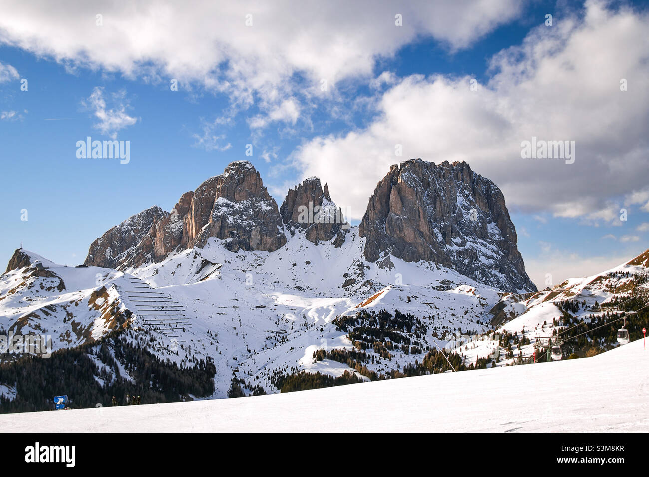 dolomiti del tirolo montagna Sassolungo Fassatal con le cime Spallone, Punta Grohmann e cinque dita a fine inverno un cielo nuvoloso Foto Stock