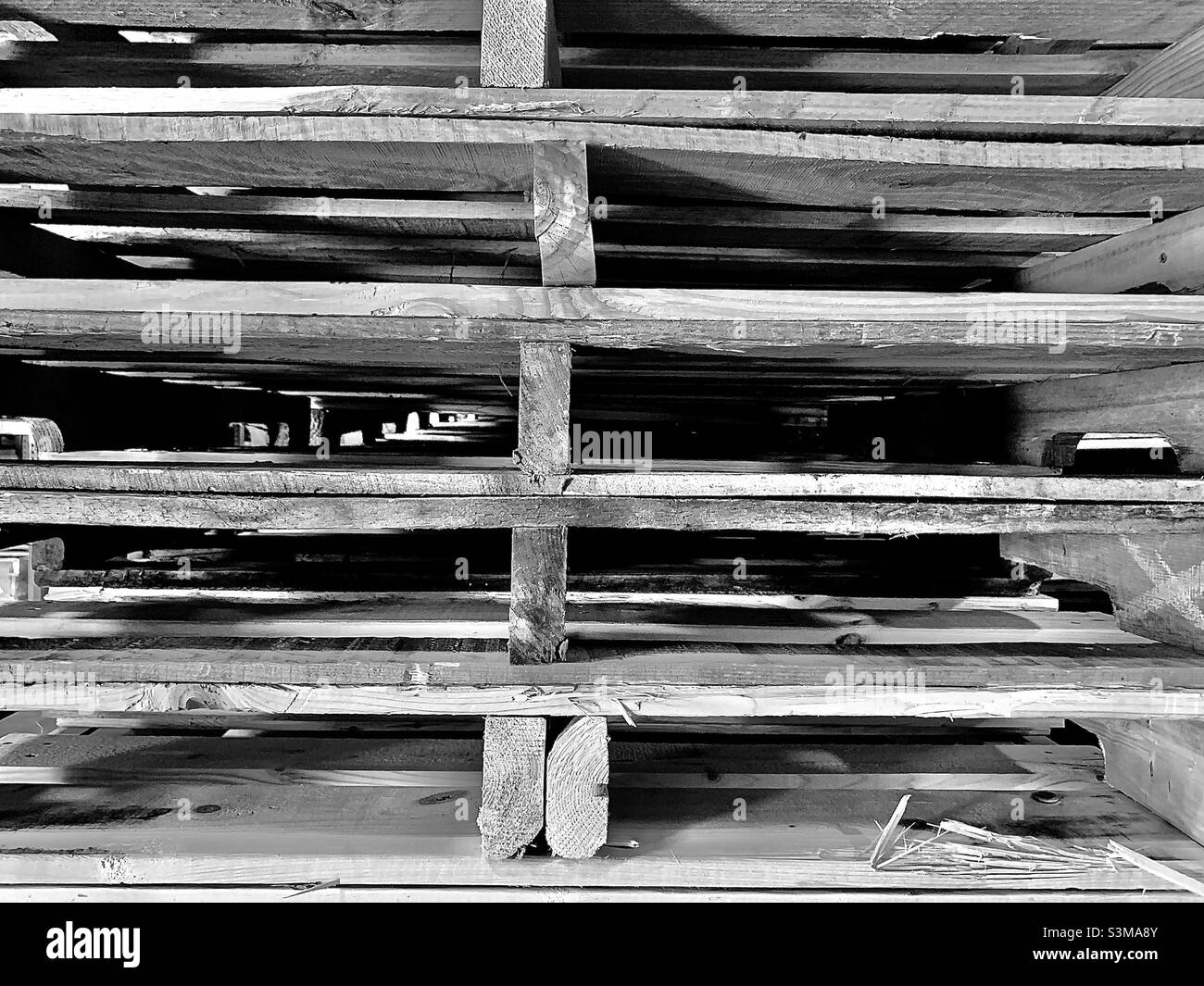Una pila di pallet in legno posti su una banchina di magazzino illuminata in bianco e nero. Foto Stock