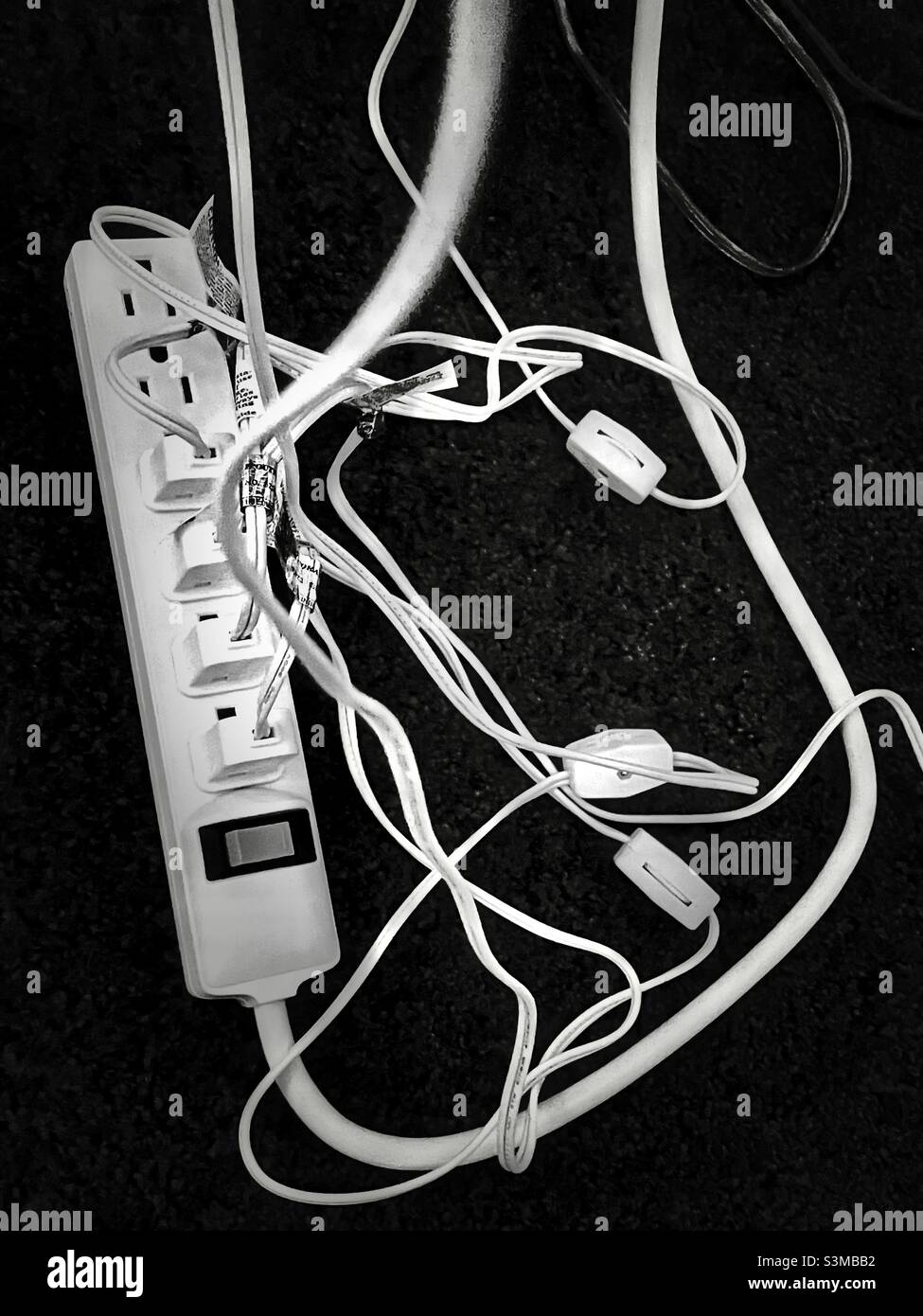 Una presa multipla sotto un tavolo del soggiorno ha prese multiple durante la stagione natalizia per ospitare tutte le decorazioni illuminate. - Immagine stock catturata con smartphone