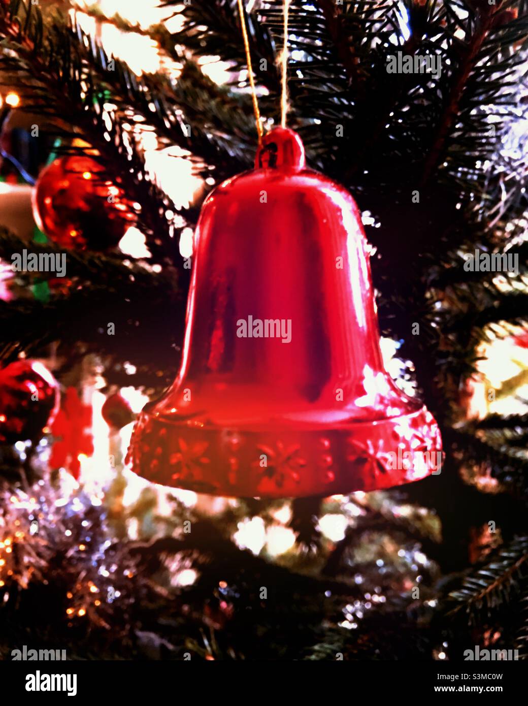 Una decorazione a campana rosso lucido appeso su un albero di Natale Foto Stock
