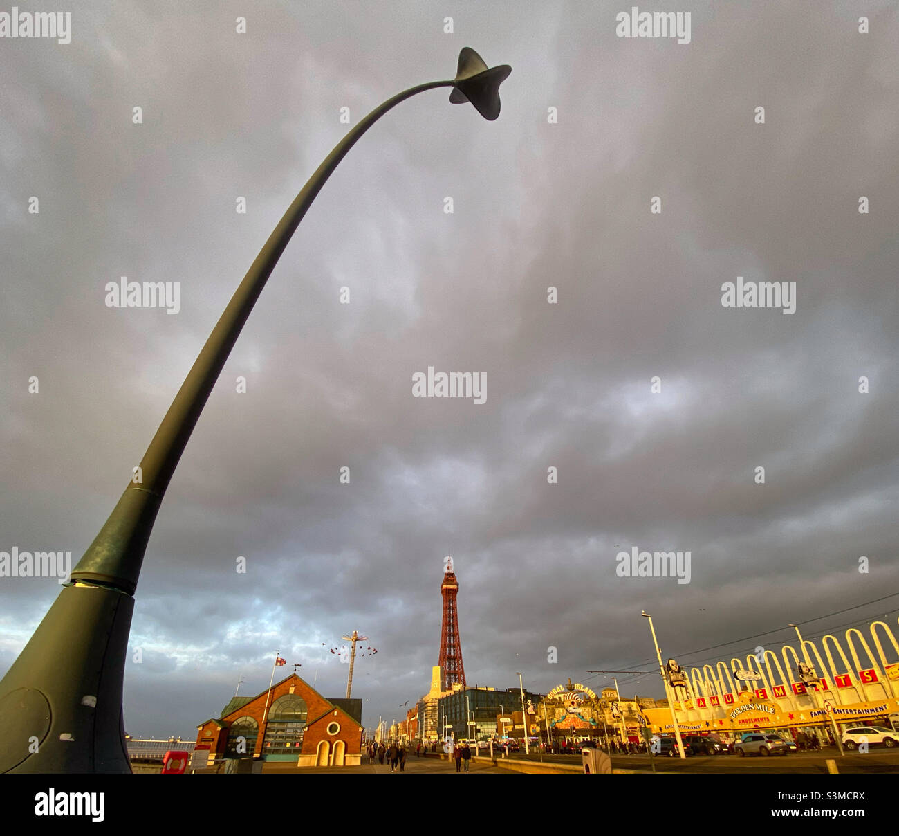 Blackpool Golden Mile incorniciato da una scultura in erba di mare piegata dal vento con Blackpool Tower in lontananza Foto Stock