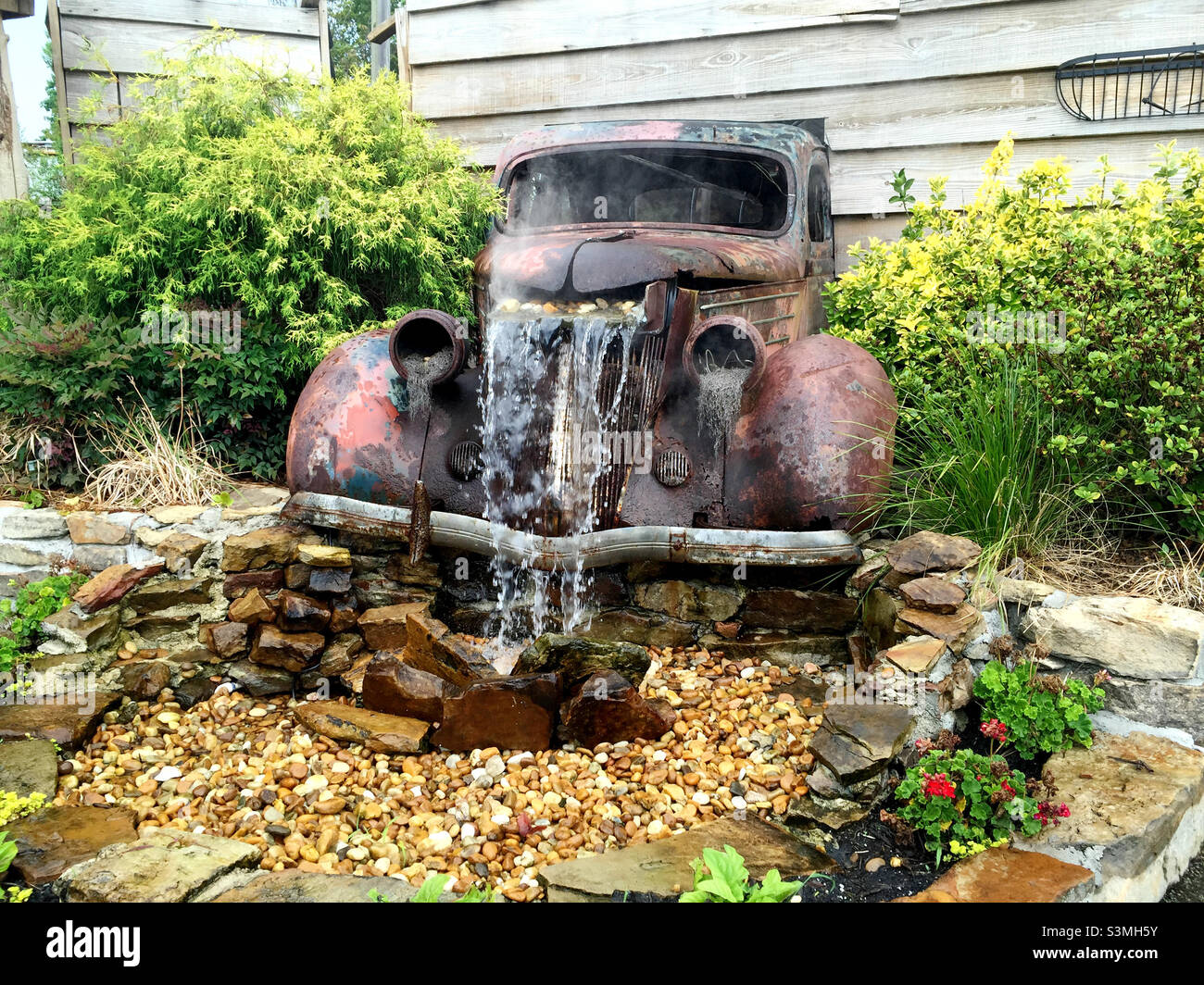 Antico camion arrugginito convertito in una fontana d'acqua giardino. Foto Stock