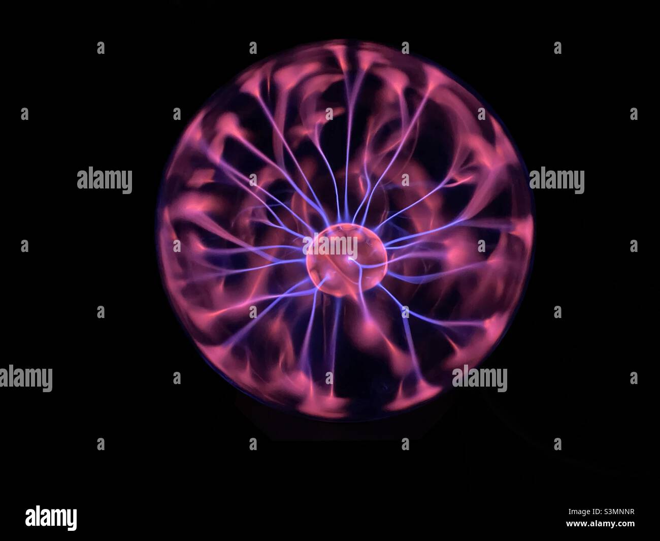 Una fotografia di un giocattolo al plasma in una stanza buia. Vivace neon rosa e viola elettrico. Foto Stock