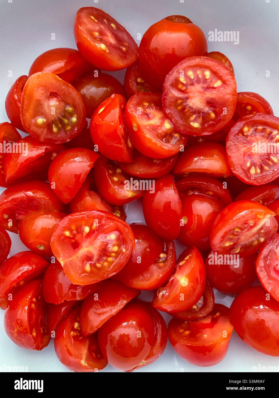 Pomodori ciliegini rossi tagliati a metà Foto Stock