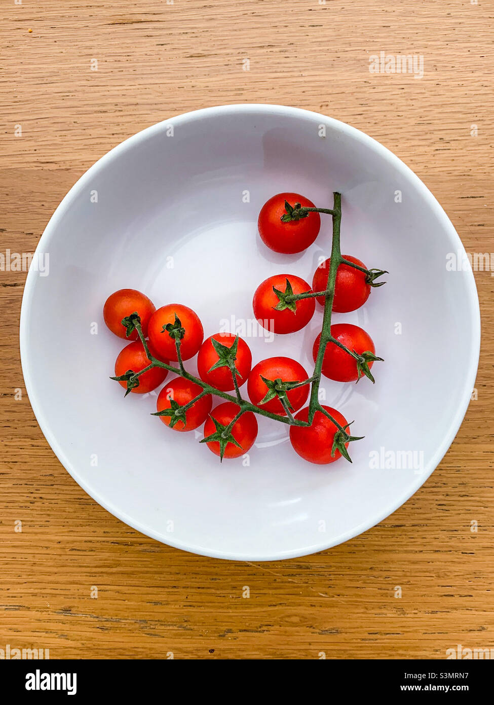 Pomodori ciliegini rossi sulla vite Foto Stock