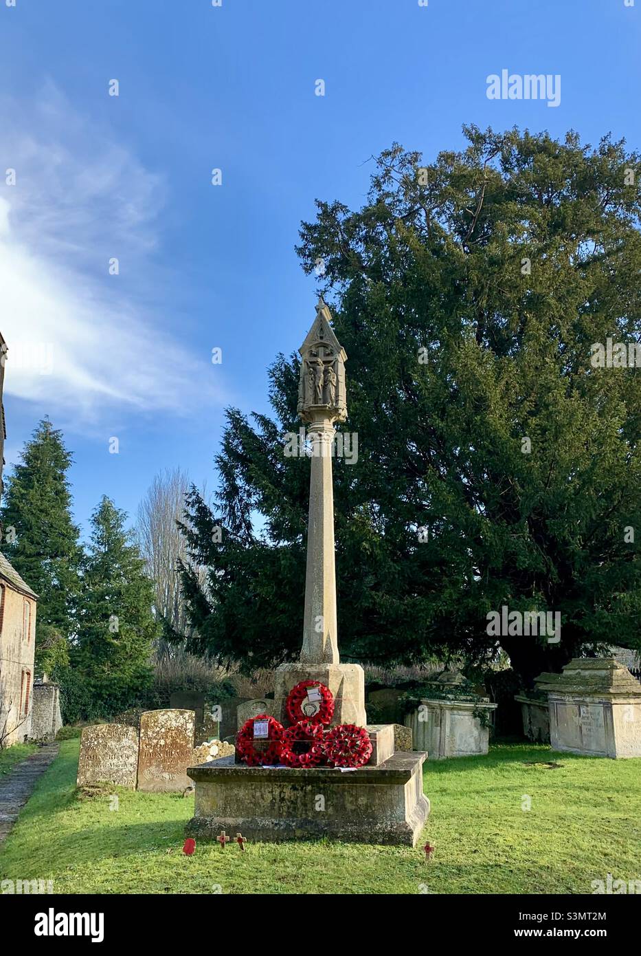 Un monumento a coloro che sono morti in guerra, in un cimitero inglese villaggio. Ghirlande a papavero in mostra Foto Stock