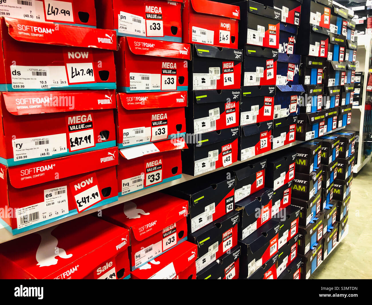 Scatole di scarpe sportive impilate su scaffali in un negozio di articoli sportivi. Foto Stock