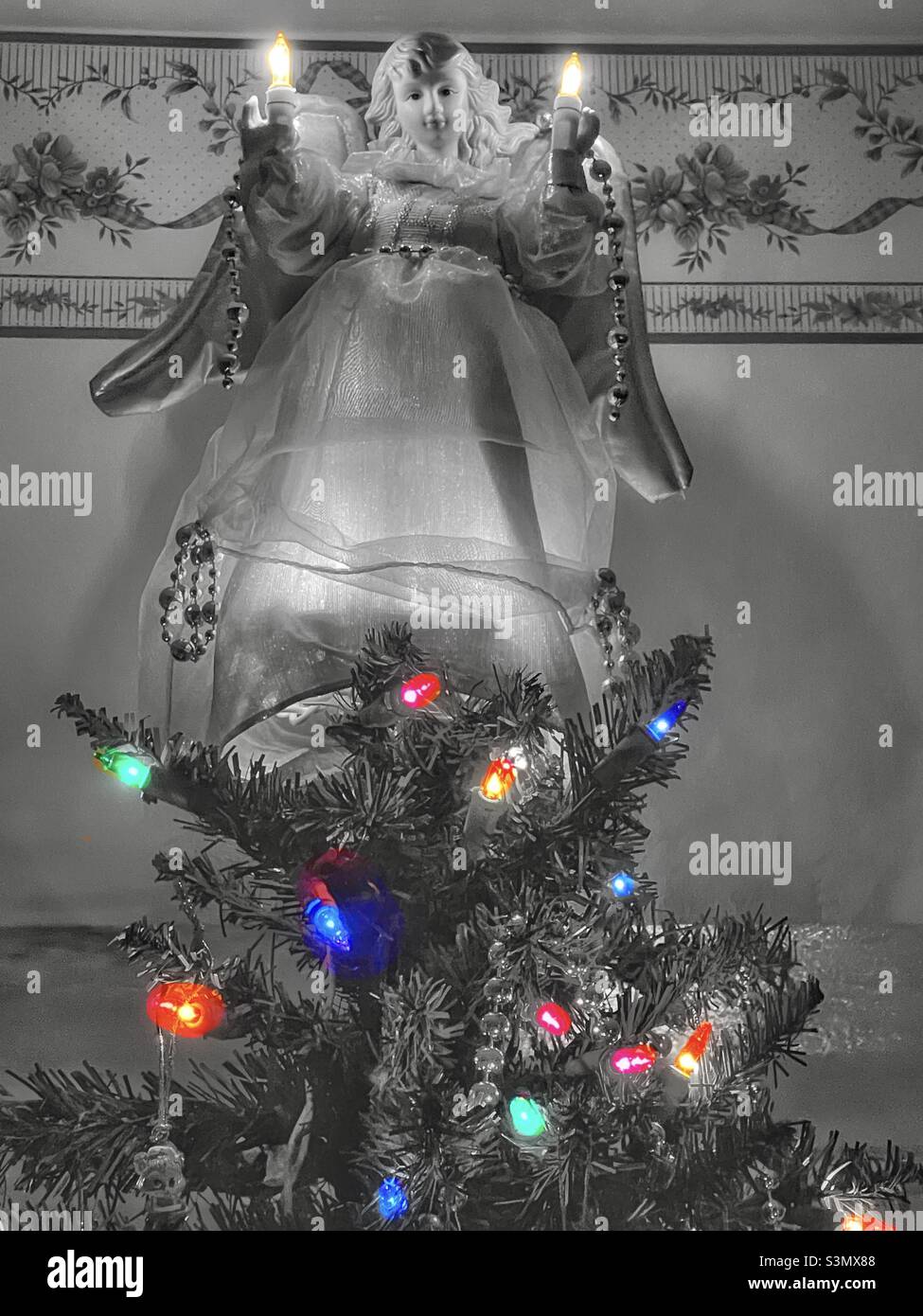 Angelo topper albero su un albero di Natale illuminato. Foto Stock