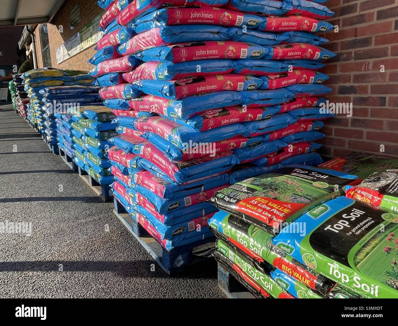 Sacchi di composto impilati fuori di un grande centro giardino - Immagine stock catturata con smartphone