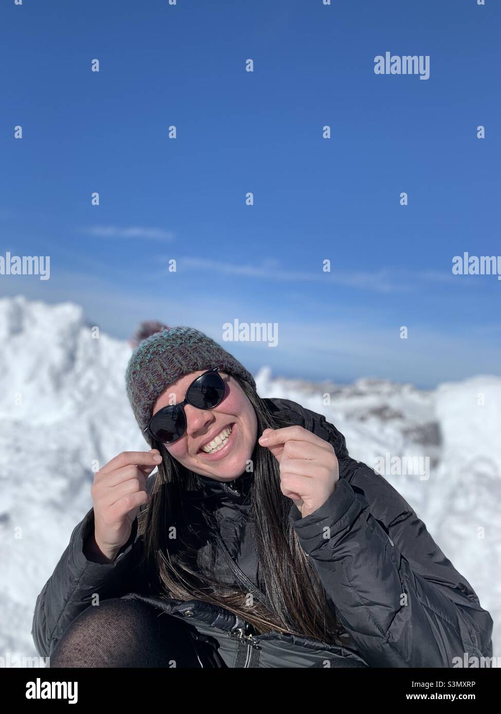Le donne sorridono facendo un gesto di cuore del dito. Montagna innevata in Engelberg dietro di lei. Cantone di Oswalden, Svizzera - Immagine stock catturata con smartphone