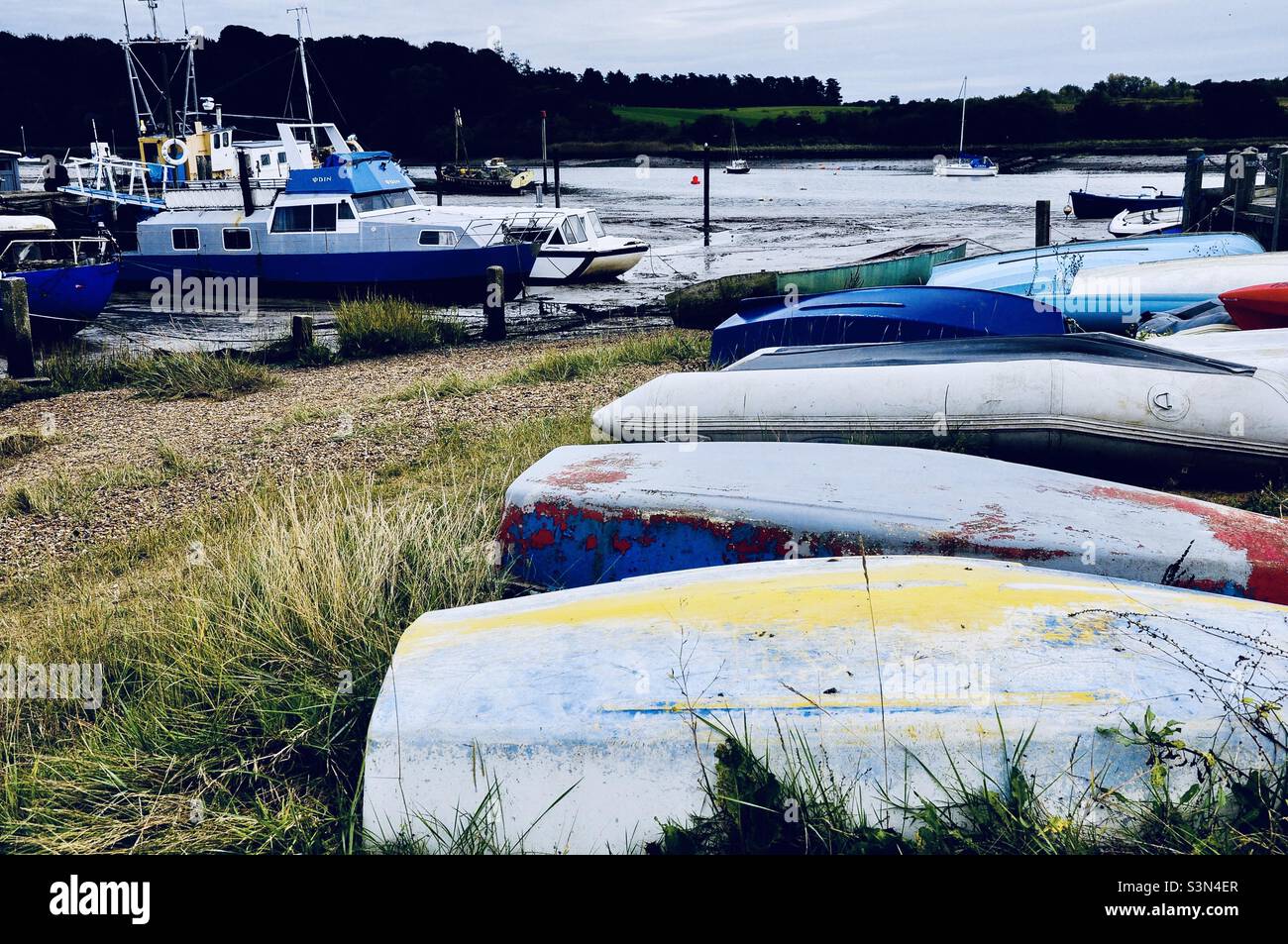 Barche ribaltate lungo la riva dell'erba - River Deben, Woodbridge, Suffolk, Regno Unito Foto Stock