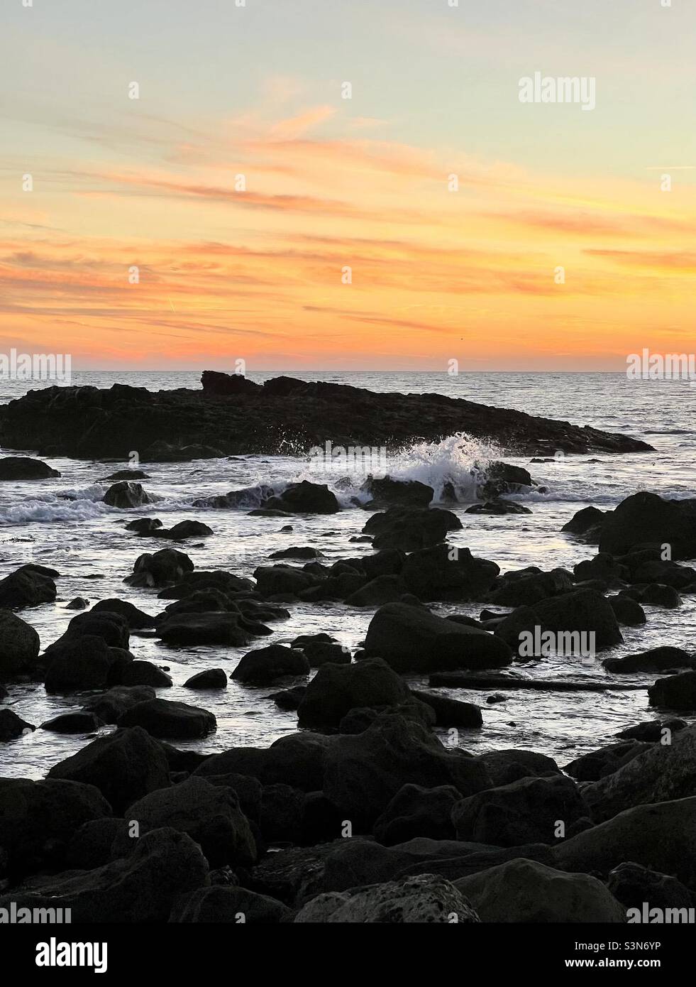 Tramonto lungo una costa rocciosa Foto Stock