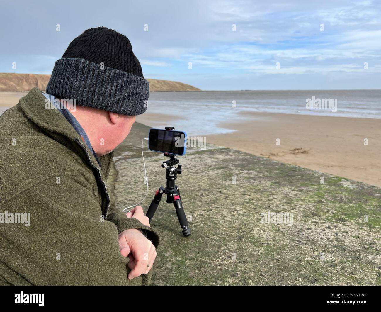 Fotografo che utilizza un iPhone montato su un mini treppiede - Immagine stock catturata con smartphone