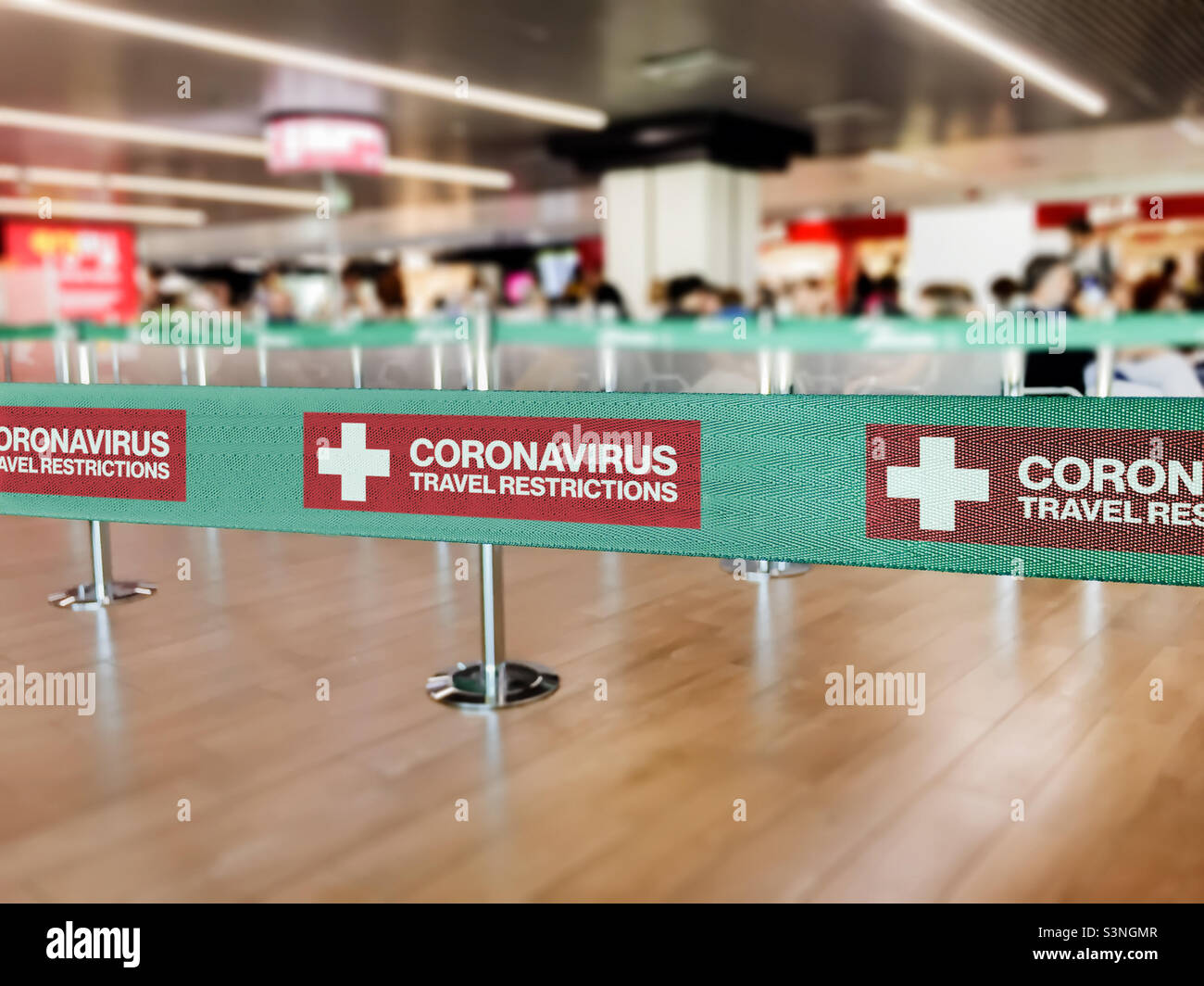 Barriera verde a nastro all'interno di un aeroporto con l'avvertimento di restrizioni di viaggio a causa della diffusione a livello mondiale di Coronavirus - Immagine stock catturata con smartphone