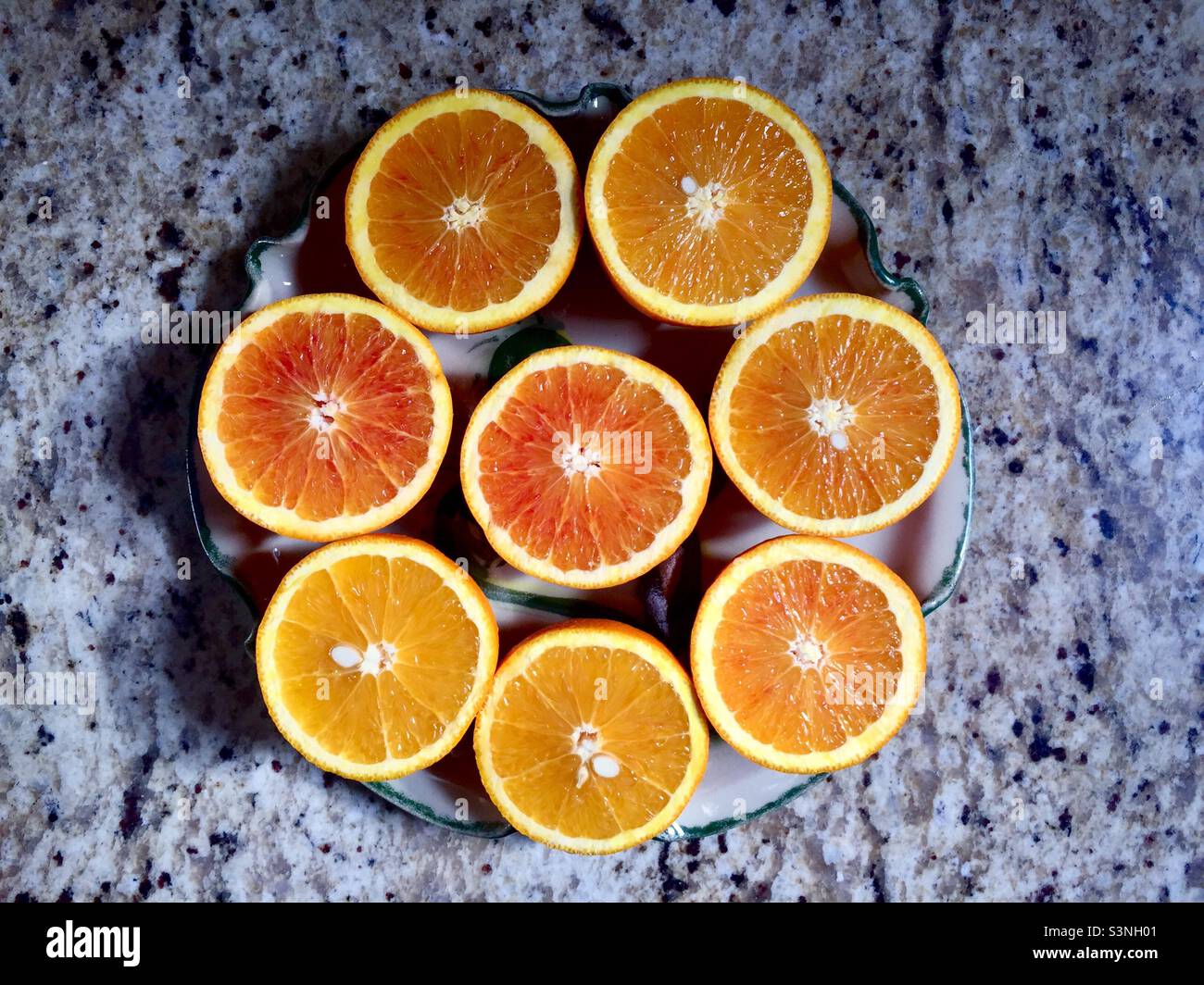 Arance fresche e succose disposte in cerchio, seduti su un bancone di granito, Ontario, Canada. Succosa, piena di vitamina C. luminosa, come il sole della Florida. Otto metà, rosa e giallo. Foto Stock