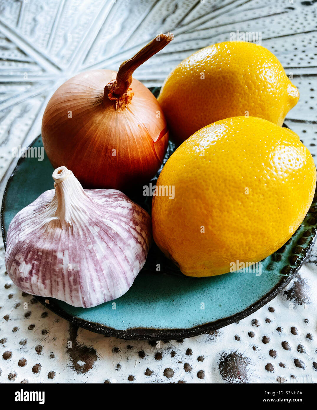 Ancora vita di un piatto con un bulbo d'aglio, cipolla fresca e due limoni - Immagine stock catturata con smartphone