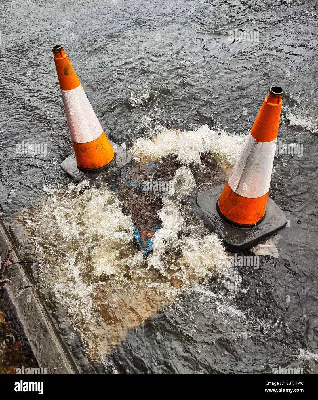 I coni di traffico segnano una botola traboccante mentre i livelli dell'acqua continuano a salire sul fiume Calder, Brighouse, West Yorkshire come Storm Eunice è seguito da Storm Franklin (20,2.22) Foto Stock