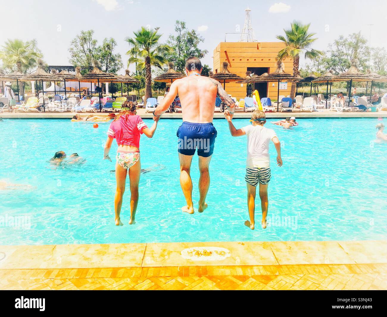 Papà e bambini che saltano in piscina Foto Stock