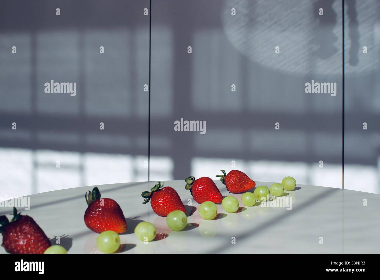 Filari di uve verdi e fragole Foto Stock