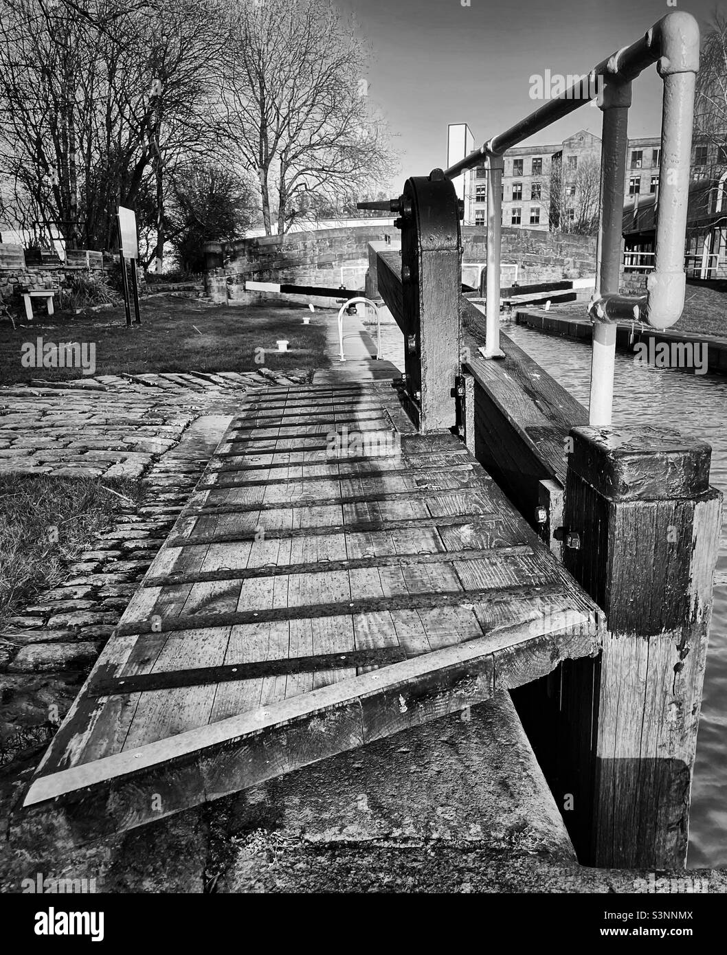 «Tempo di apertura» un lucchetto chiuso sul canale con i vecchi mulini in pietra del passato industriale sullo sfondo Foto Stock