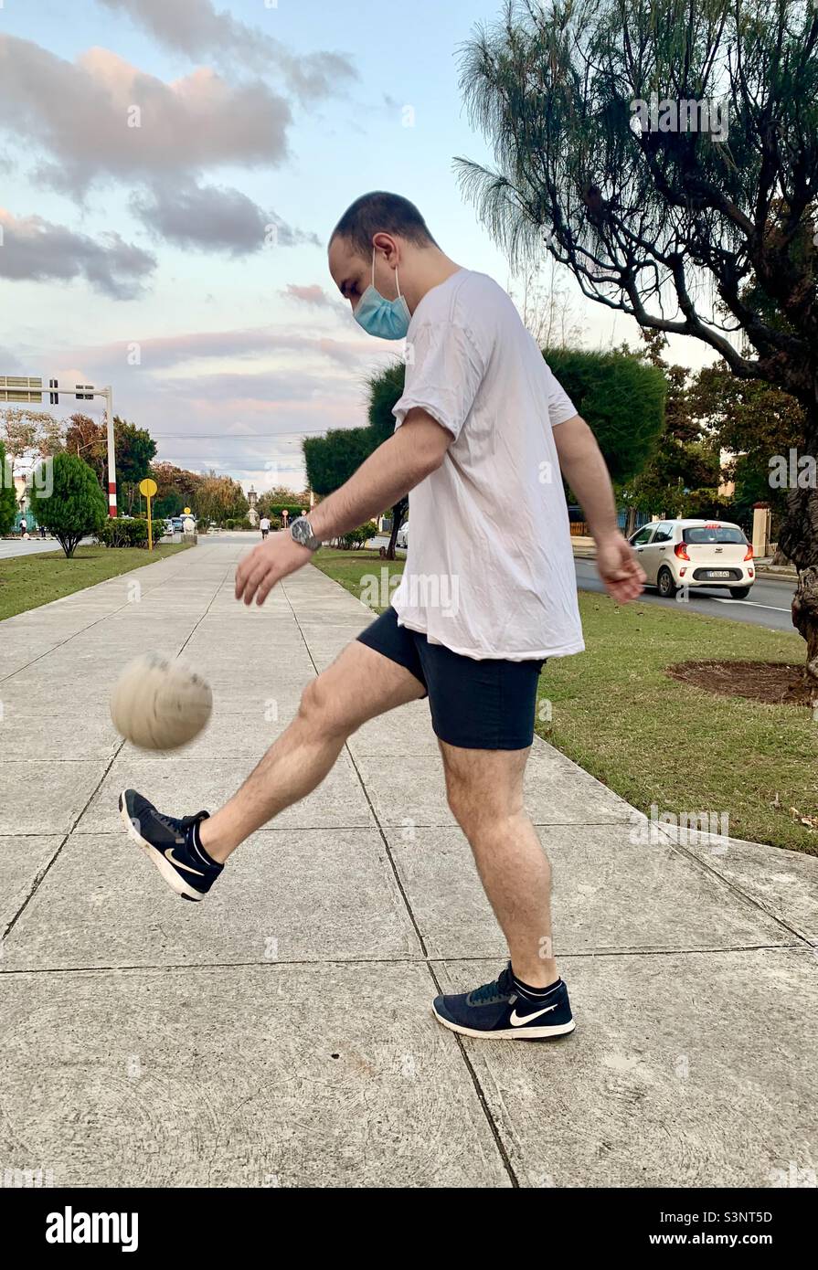 uomo di 30 anni che calcia la palla di calcio in aria. Salute mentale e concetto di attività fisica. L'Avana, Cuba, Caraibi. Foto Stock