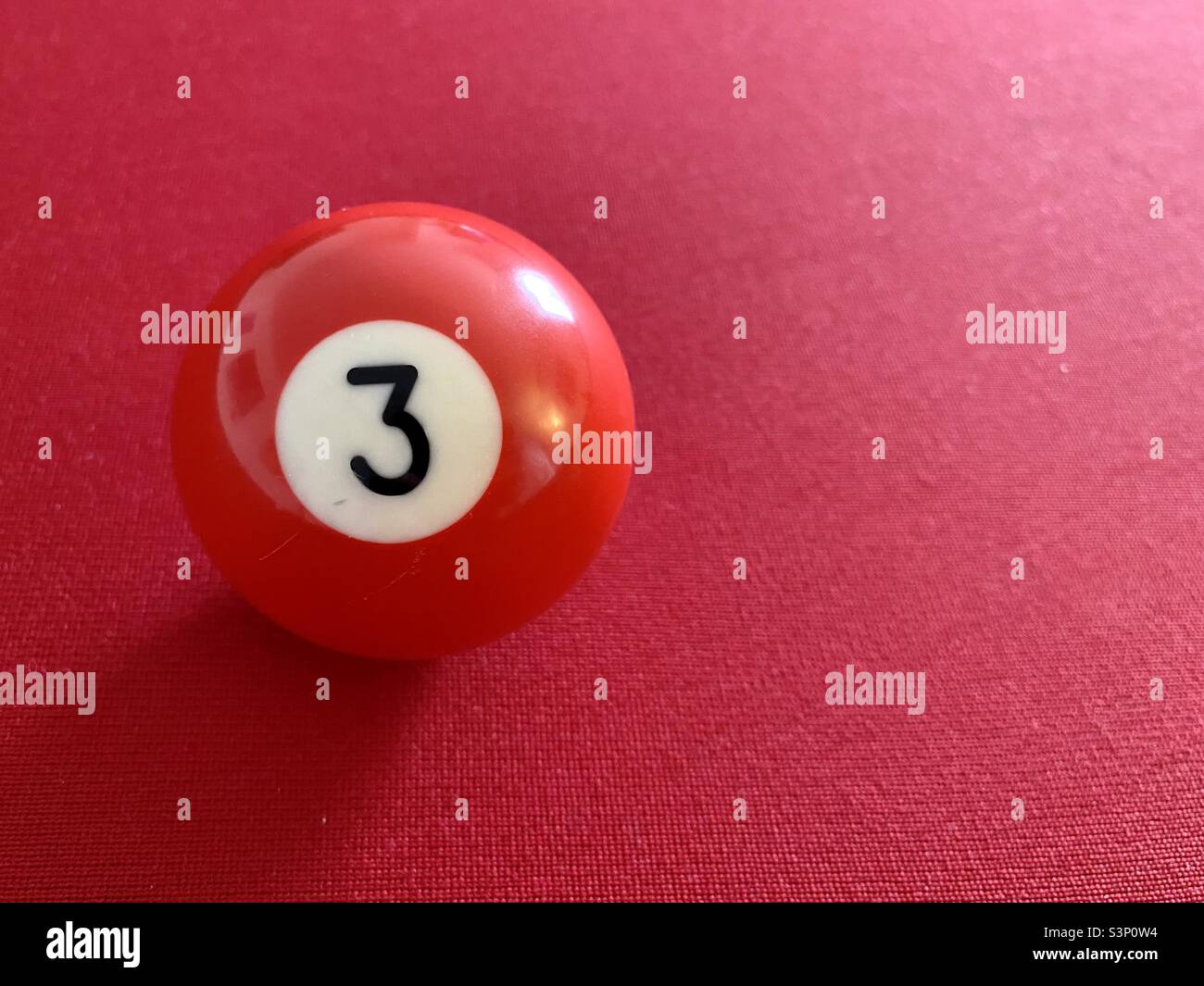 Pallina da piscina rossa su sfondo baize rosso Foto Stock