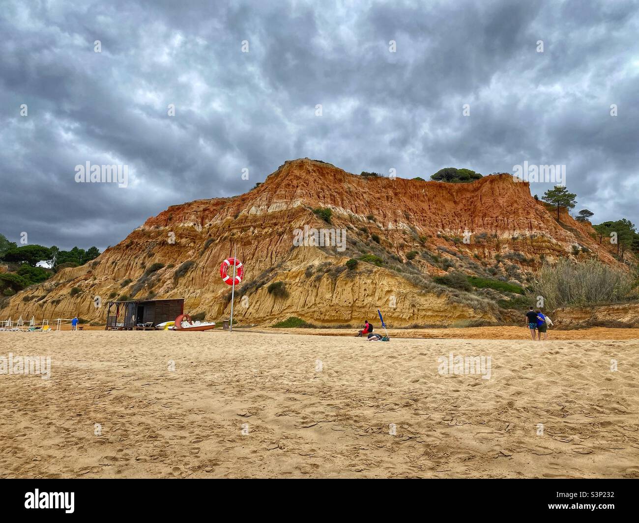 Giornata nuvolosa sulla spiaggia di Praia da Falesia con rocce di arenaria e anello galleggiante rosso, Algarve, Portogallo. Foto Stock