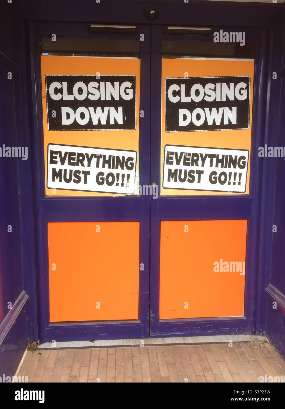 Le porte di negozi con avvisi arancioni che dicono "chiusura" e "tutto deve andare!" - Immagine stock catturata con smartphone