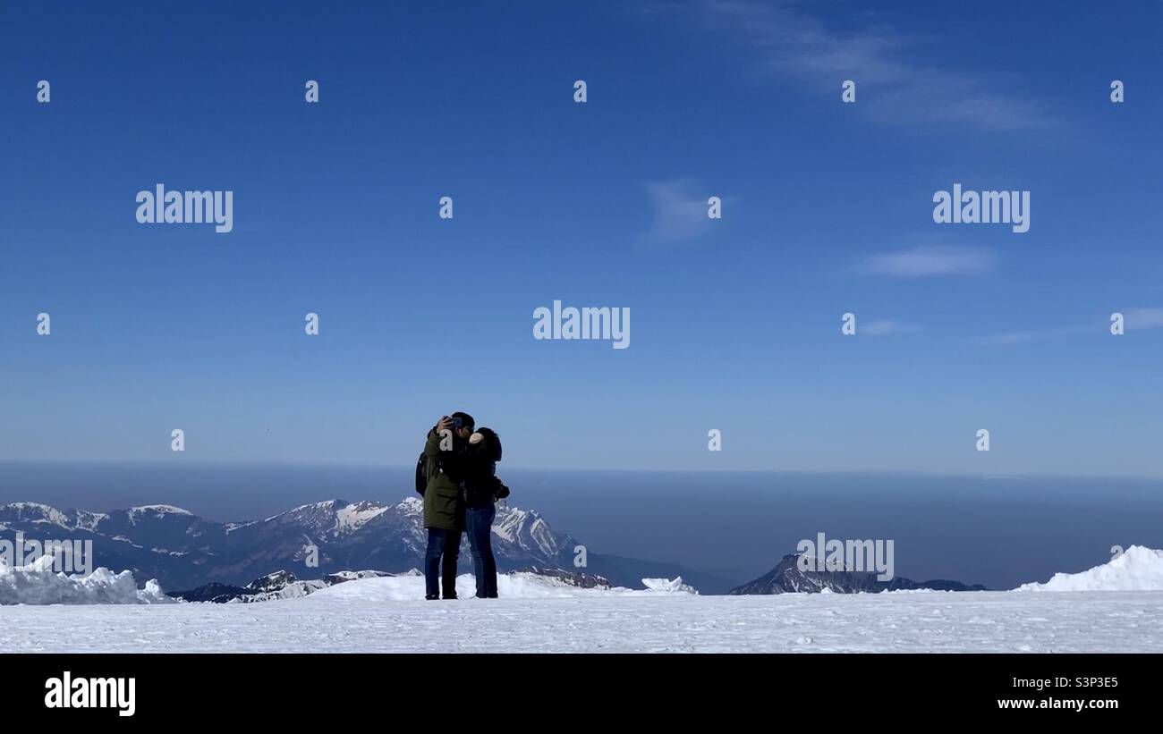 La coppia ha un bacio mentre prende un selfie sulla cima del Monte Titlis, Engelberg, Svizzera. Foto Stock