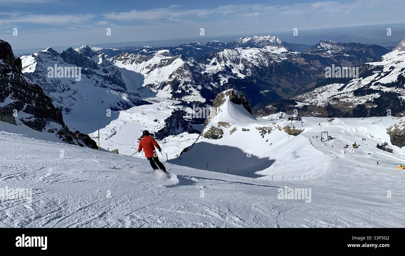 Sciatore sulla pista al Monte Titlis guardando verso Engelberg, Svizzera. Foto Stock