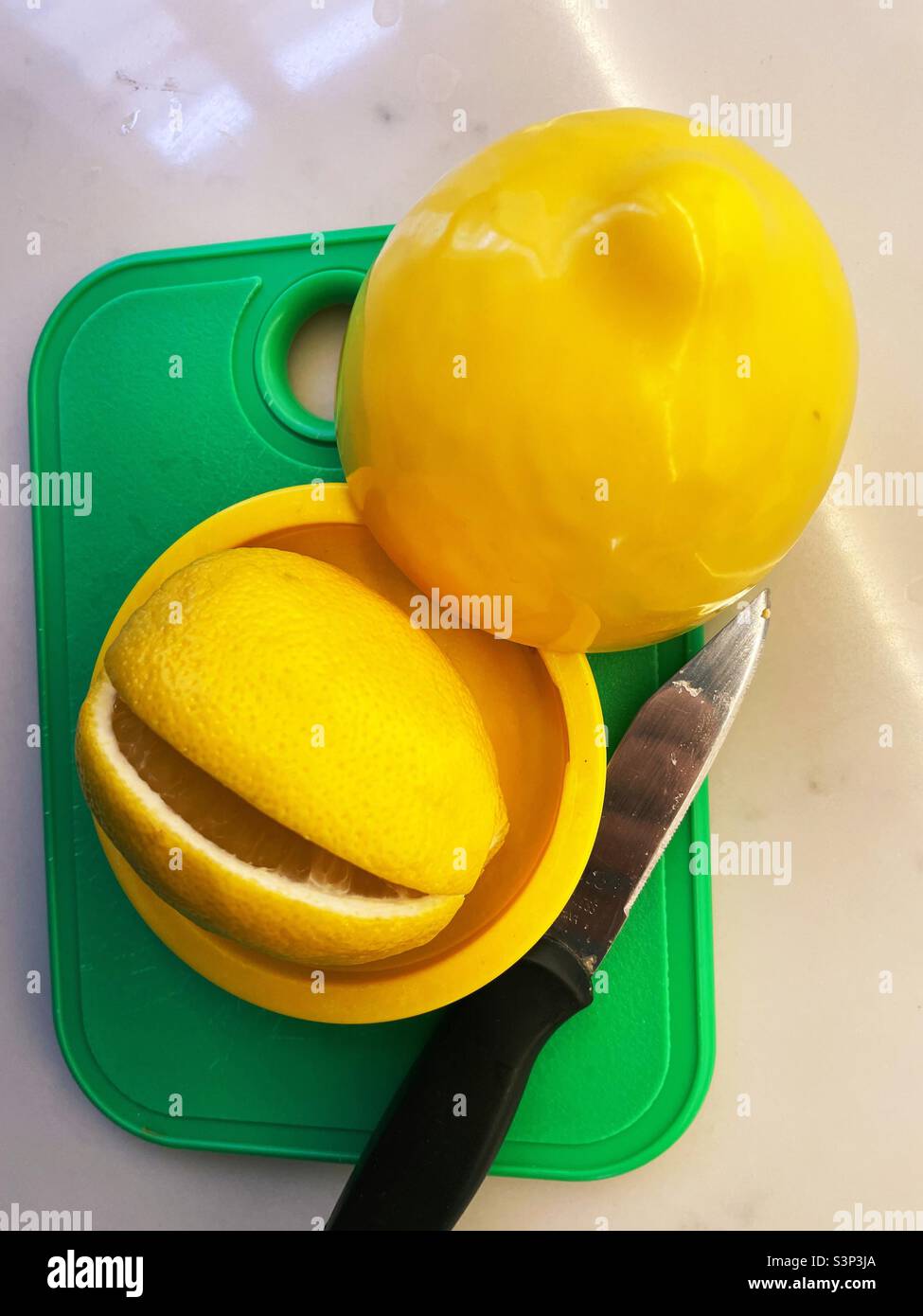 Primo piano di un limone fresco affettato su un tagliere verde accanto ad un contenitore di plastica, 2022, USA - Immagine stock catturata con smartphone