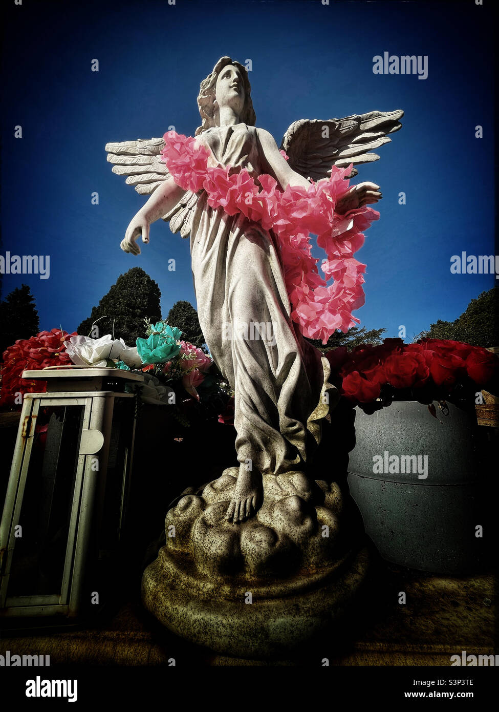 Statua dell'Angelo con ghirlanda floreale rosa nel cimitero di East Finchley - Immagine stock catturata con smartphone