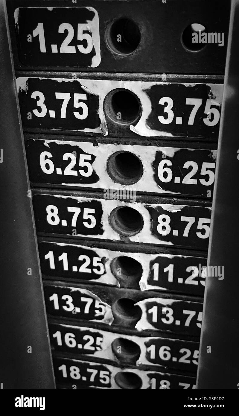 'Peso il vostro turno' una pila di pesi ben usata su una macchina da palestra in bianco e nero Foto Stock