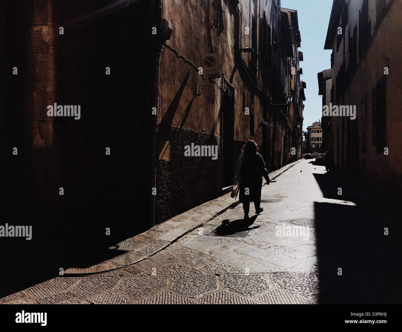 Immagine a contrasto elevato di una donna che cammina su una strada stretta a Firenze Italia Foto Stock