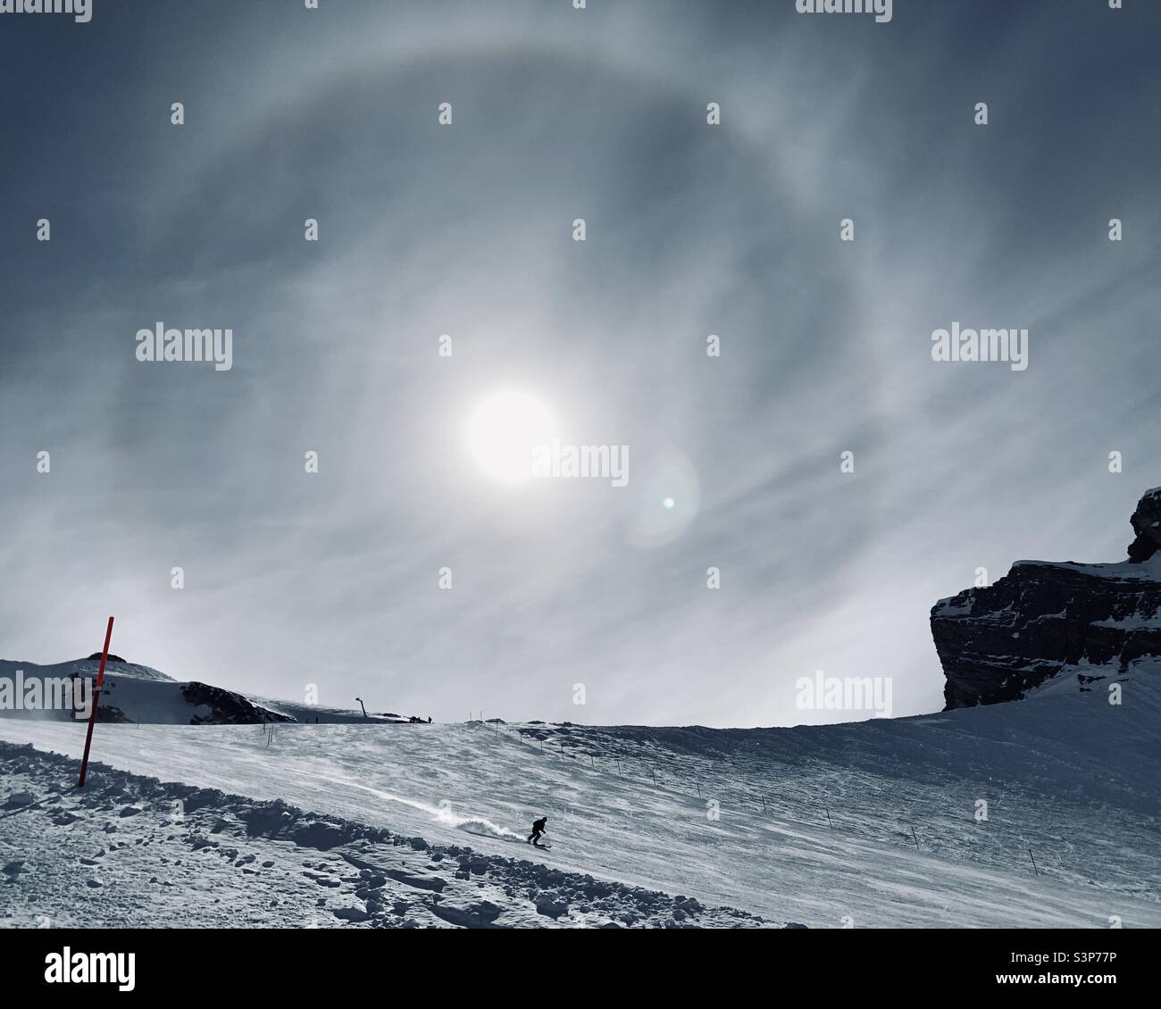 Sciatore solista sul Monte Titlis con un arcobaleno circolare nel cielo Foto Stock