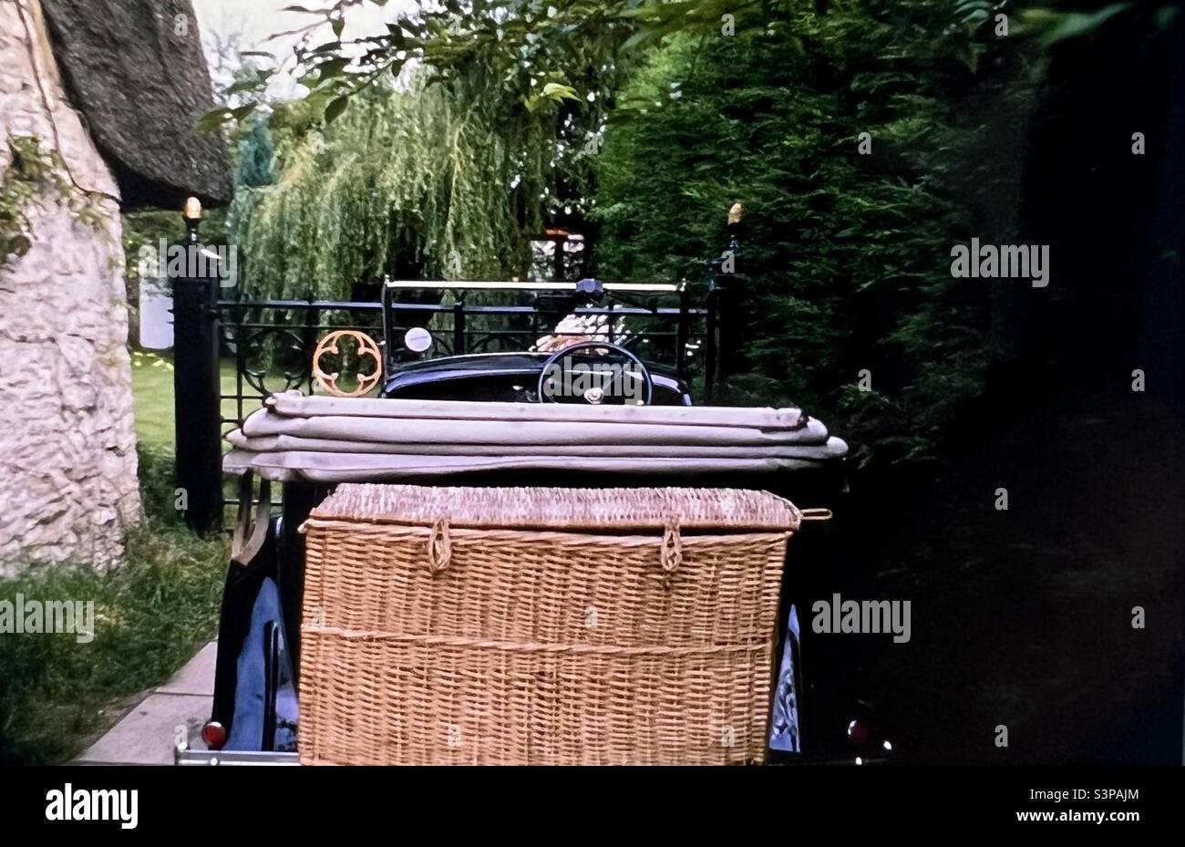 Auto convertibile d'epoca con stivale in vimini parcheggiato all'esterno della casa con tetto in paglia Oxfordshire Foto Stock