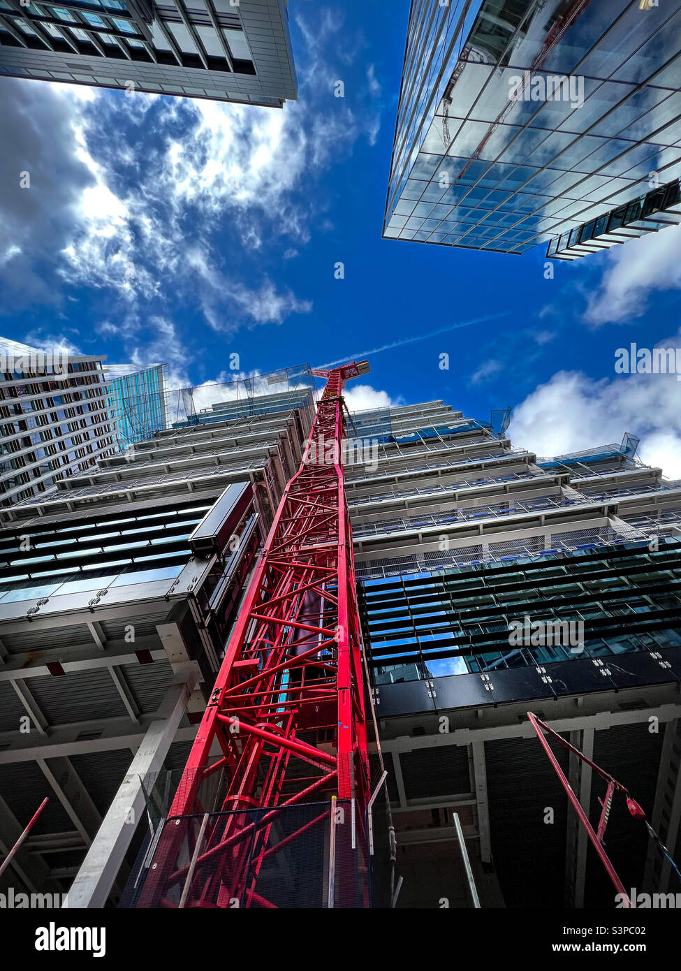 Gru rossa che costruisce alti edifici nel quartiere finanziario della City of London, Regno Unito. Gennaio 2022. - Immagine stock catturata con smartphone