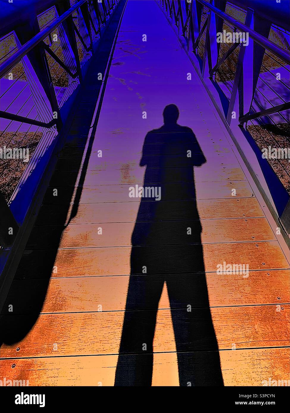 L'ombra dell'uomo si getta su un piccolo ponte del parco cittadino a Salt Lake City, Utah, USA. Le alterazioni digitali hanno creato i gradienti di colore e il contrasto netto per un effetto artistico. - Immagine stock catturata con smartphone