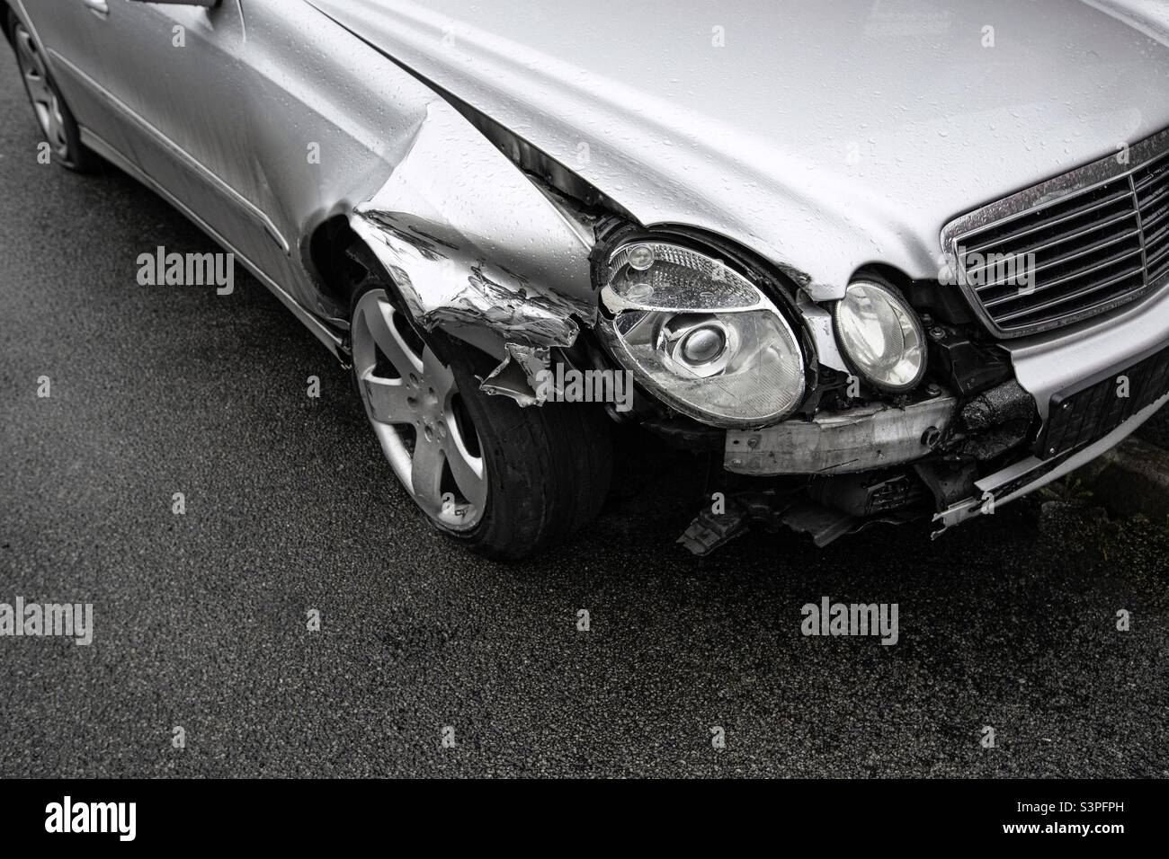 Un'automobile che è stata coinvolta in un incidente stradale con danni ai fari sul parafango anteriore e alla ruota con spazio di riproduzione - Immagine stock catturata con smartphone