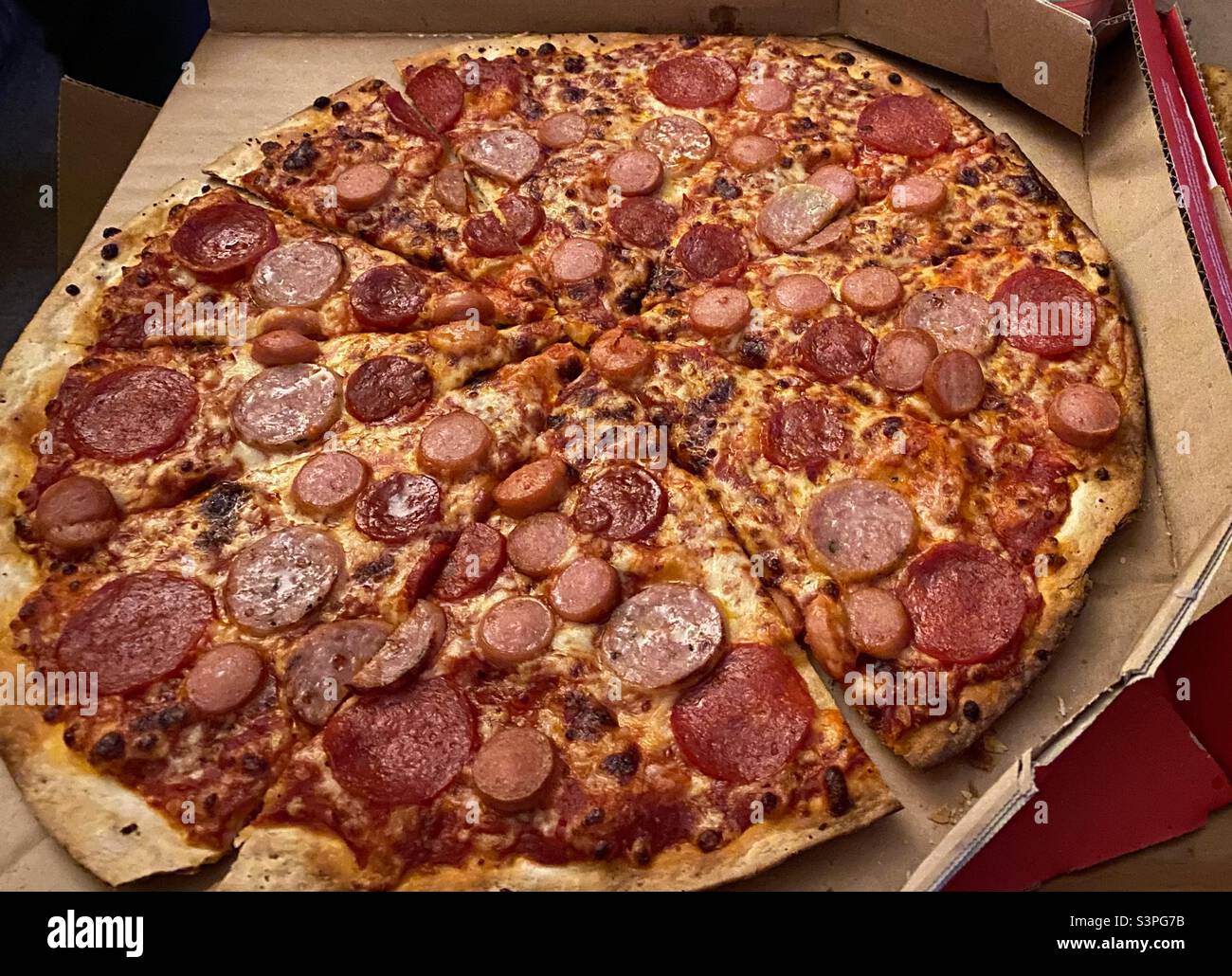 Primo piano di una pizza gustosa in una scatola da asporto, cotta e pronta a mangiare - Immagine stock catturata con smartphone