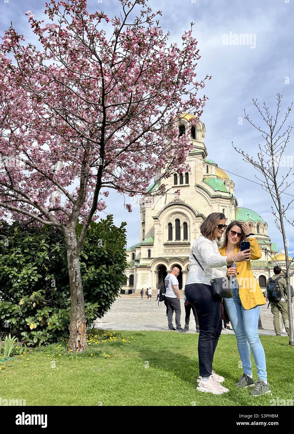 Le donne che prendono selfie da un albero di ciliegia giapponese o Sakura in piena fioritura alla Cattedrale di St. Alexander Nevsky a Sofia, Bulgaria Foto Stock