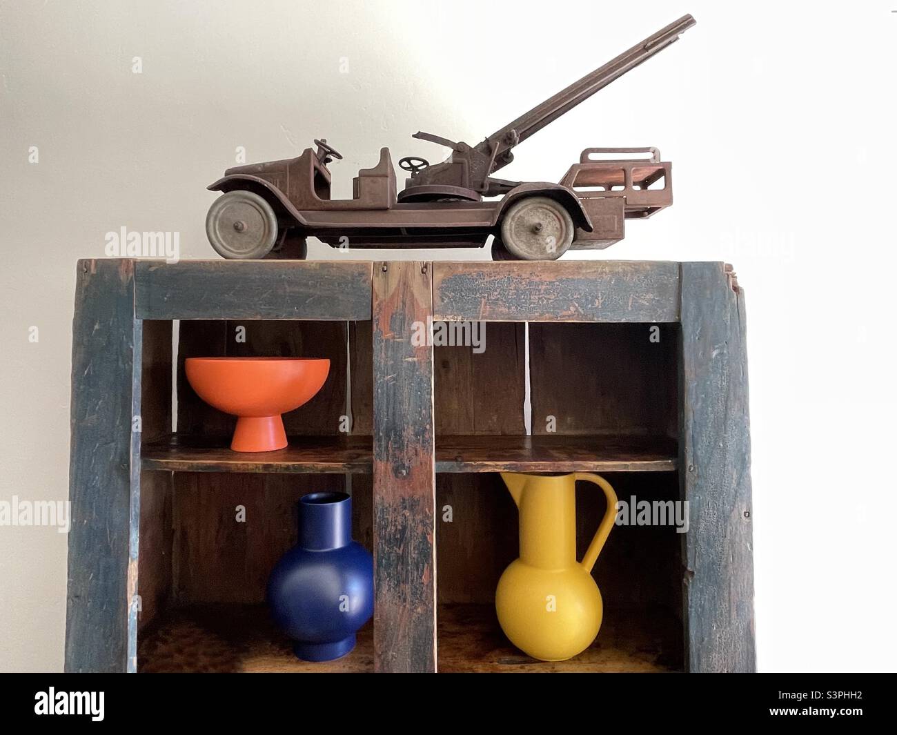L'arredamento include una libreria antica, vasi colorati e un carrello tagliafuoco in miniatura metallico arrugginito. Foto Stock