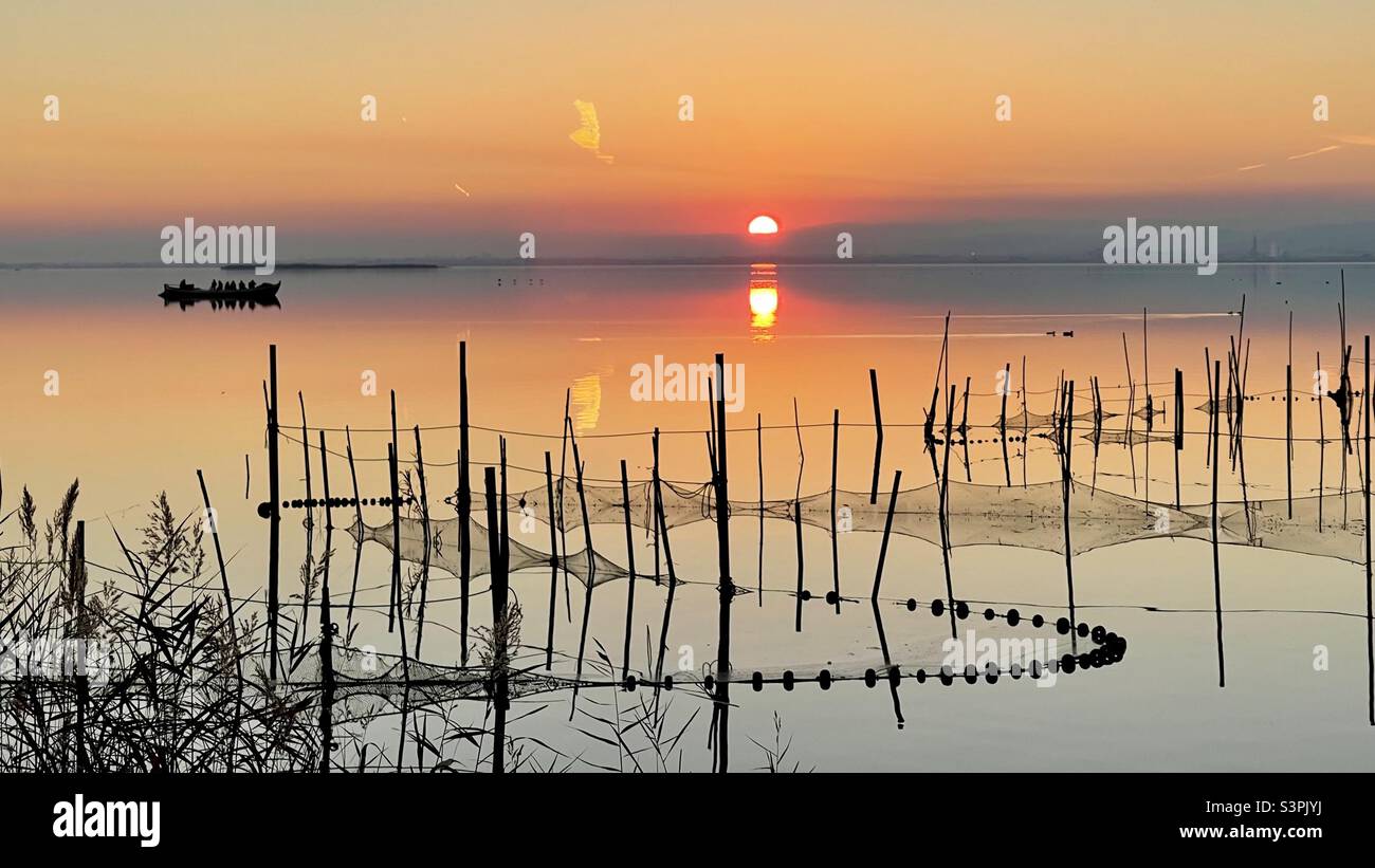 Albufera di Valencia. Puesta de sol y redes de pesca . reti da pesca inchiodate con canne al fondo poco profondo. Foto Stock