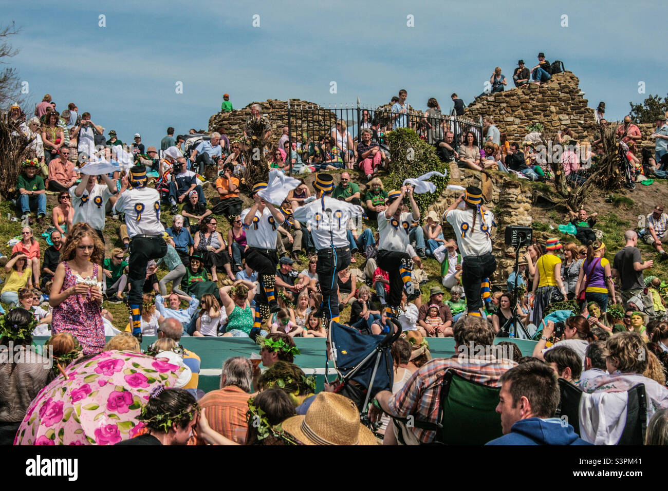 Una grande folla si riunisce all'interno delle mura del castello, guardando una squadra di danza Morris esibirsi sul palco presso le feste tradizionali di Jack in the Green di Hastings. Regno Unito, maggio 2008 - Immagine stock catturata con smartphone