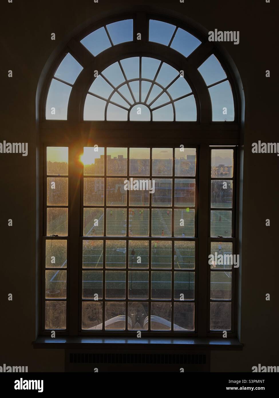 Guardando fuori sul campo di calcio della Roosevelt High School di Seattle al tramonto attraverso una classica finestra ad arco. - Immagine stock catturata con smartphone